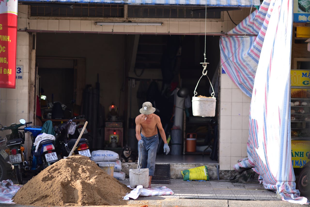 hero-img-02 A male worker in an urban setting handles construction materials. The scene captures everyday labor activities outdoors.