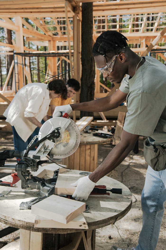 gallery-5 Focused carpenter using a circular saw at an outdoor construction site, cutting wood precisely.